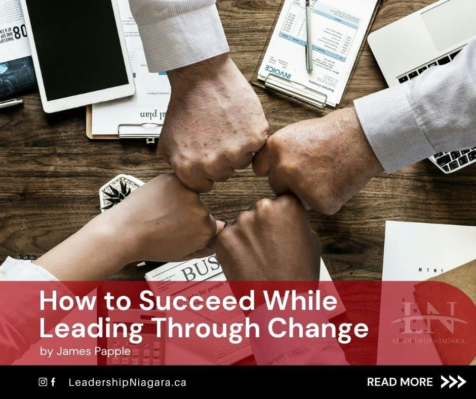 Four team members bumping fists at the same time over a work desk with papers and other work materials on it. Below, the title 'Leading Through Change' by James Papple with Leadership niagara's website and social media icons.